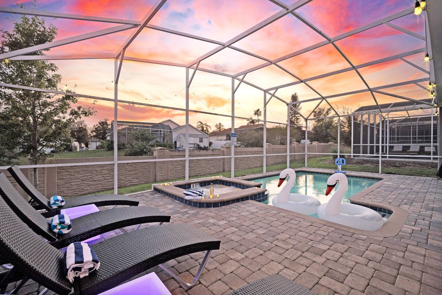 Sun loungers with LED side tables line the screened pool deck at sunset