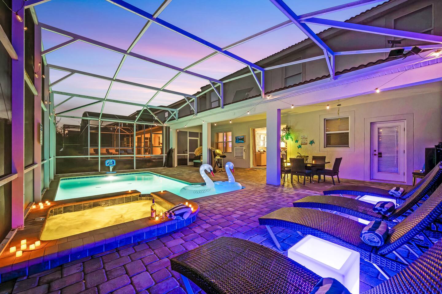 Evening lanai with lit pool, candlelit spa, and covered outdoor dining