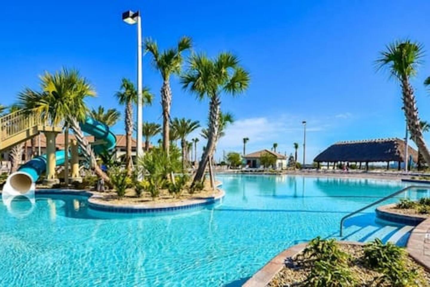 Resort pool with twisting waterslide surrounded by palms