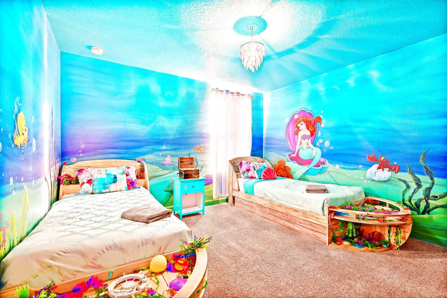 Little Mermaid room with two twin beds, shipwreck toy chests, and undersea mural