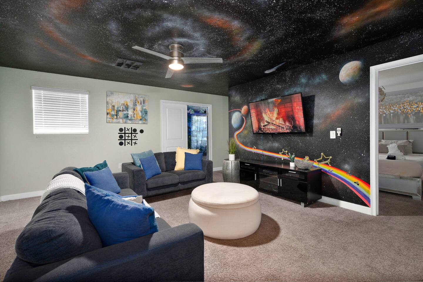 Movie loft sectional facing the TV against a starry galaxy mural wall