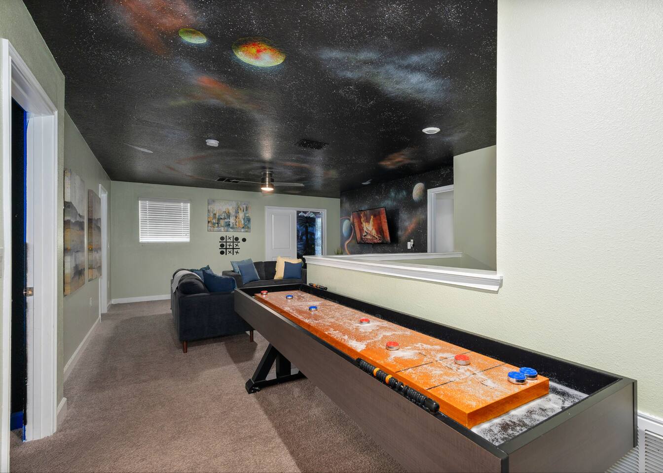 Loft shuffleboard table beneath the painted night-sky ceiling