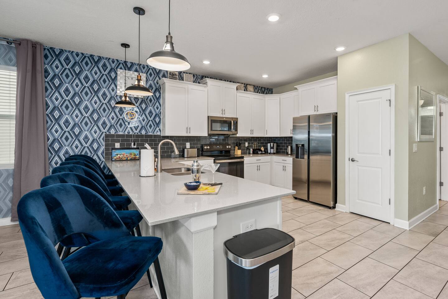 Open kitchen with quartz island bar seating, stainless appliances, and bold diam