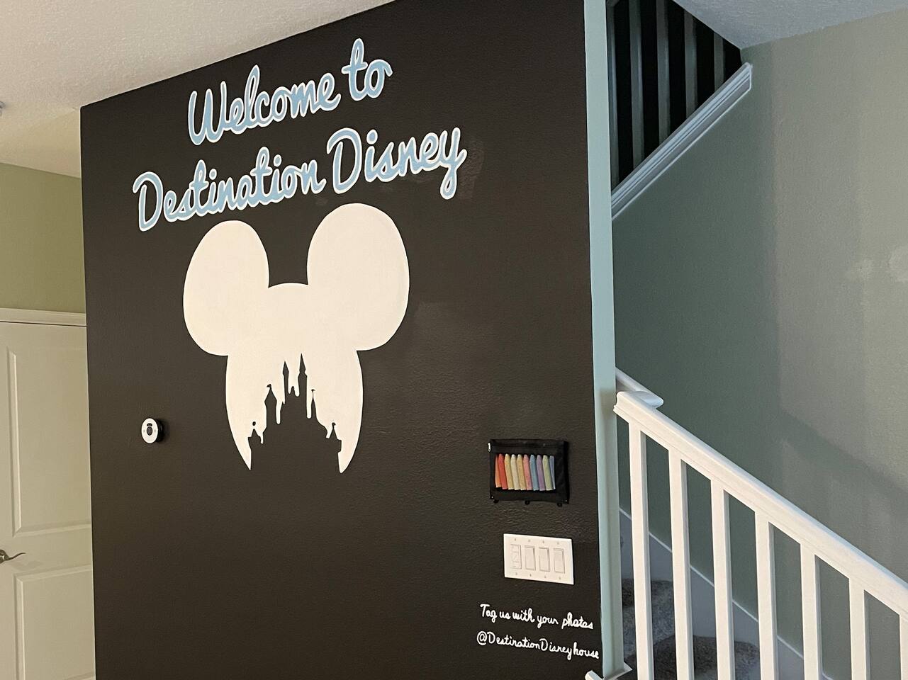 Hand-painted welcome chalkboard wall greeting guests at the stairs