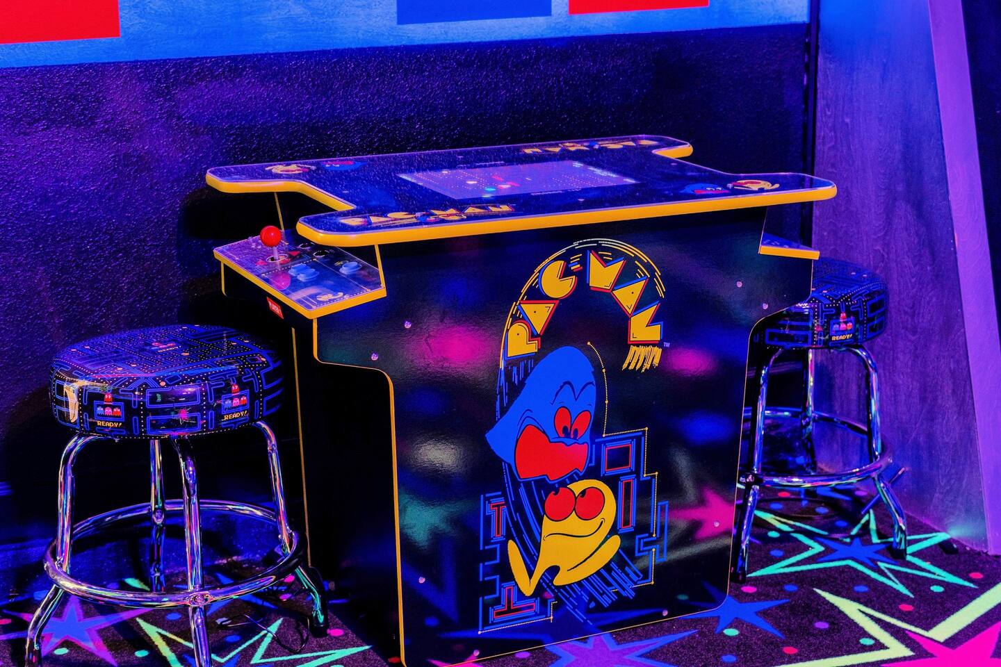 Two-player Pac-Man cocktail arcade table with matching stools in the game room