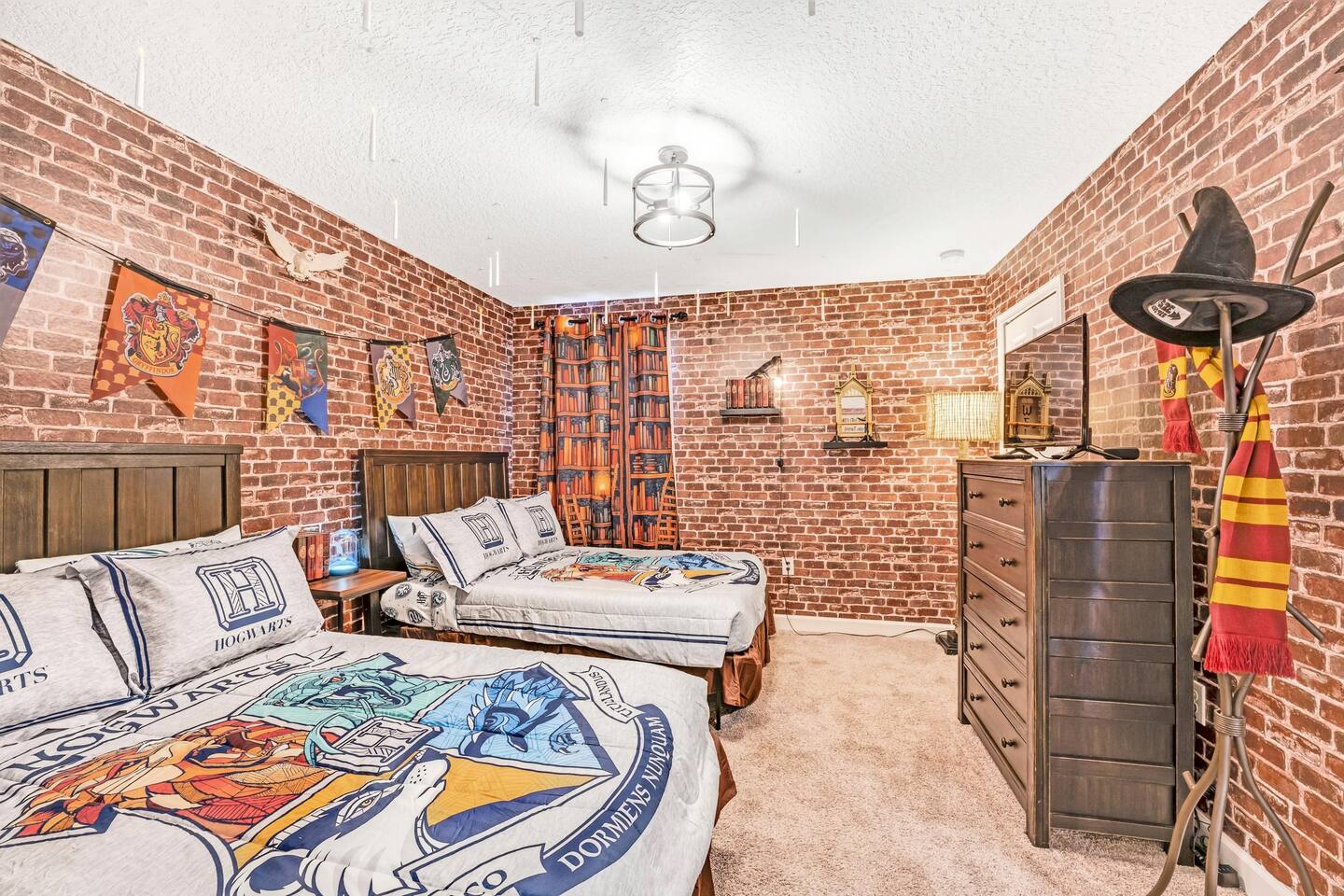Wizard-themed room with bookshelf curtains, dresser TV, and scarf-draped coat st