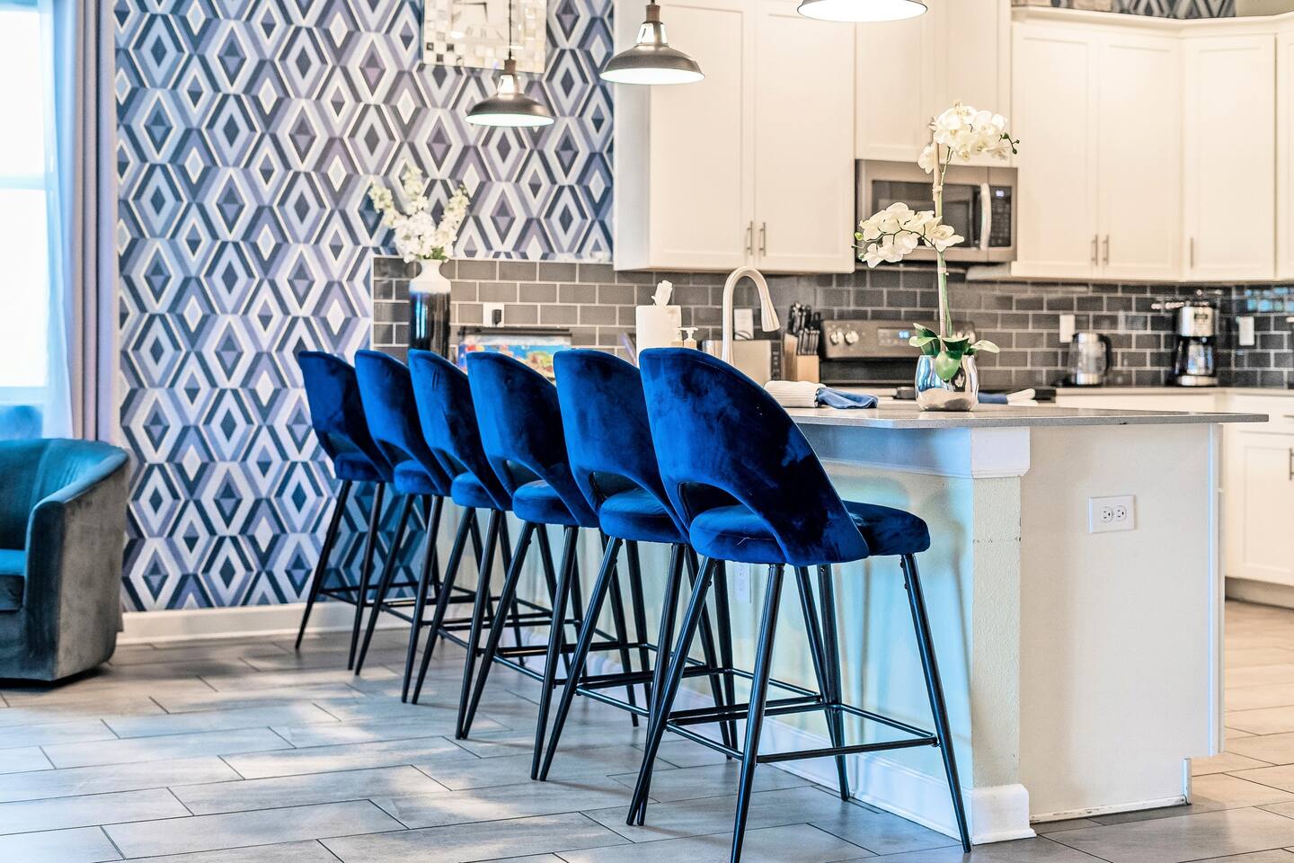 Breakfast bar with six velvet counter stools and geometric accent wall