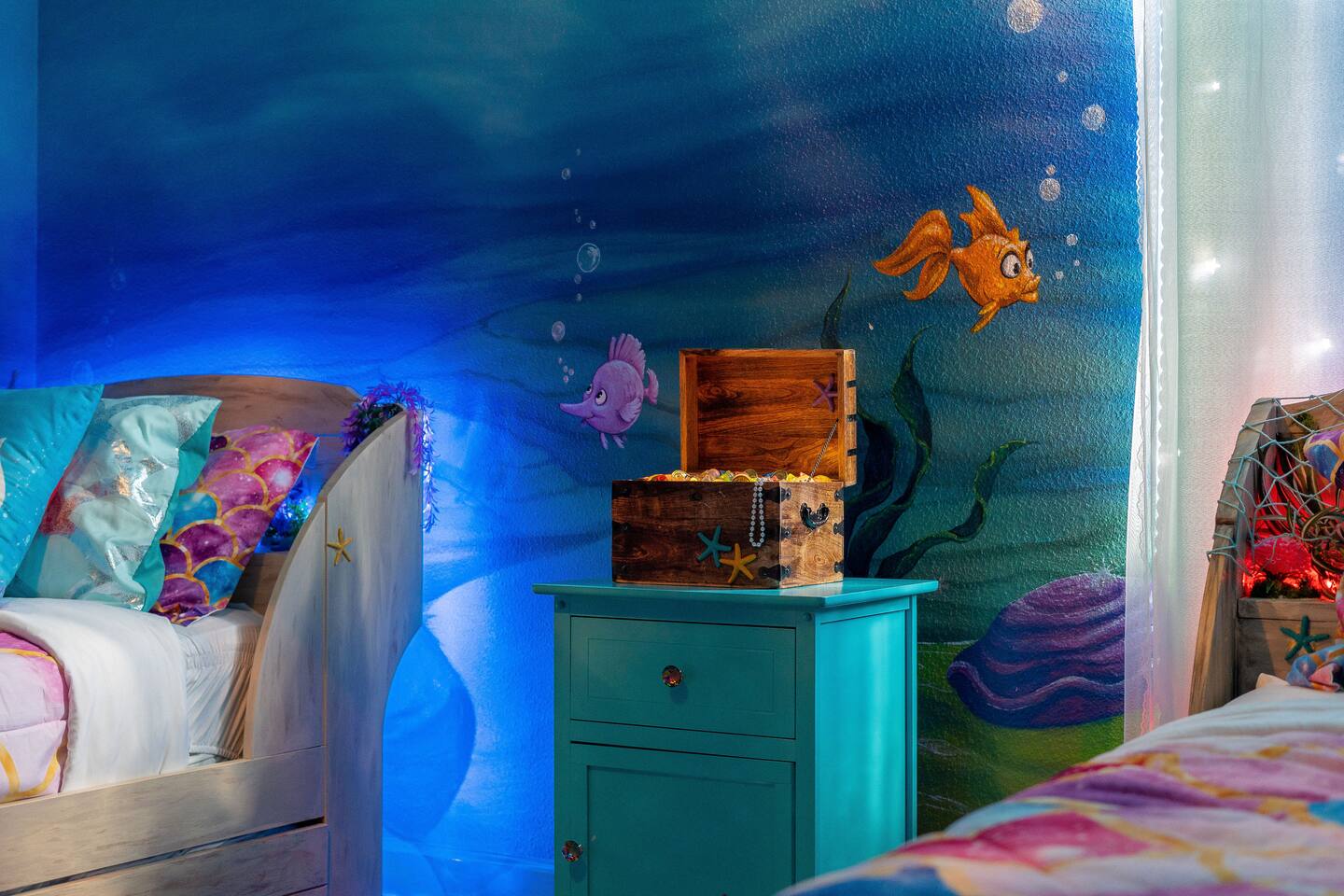 Under-the-sea mural detail with treasure-chest accent beside the boat beds