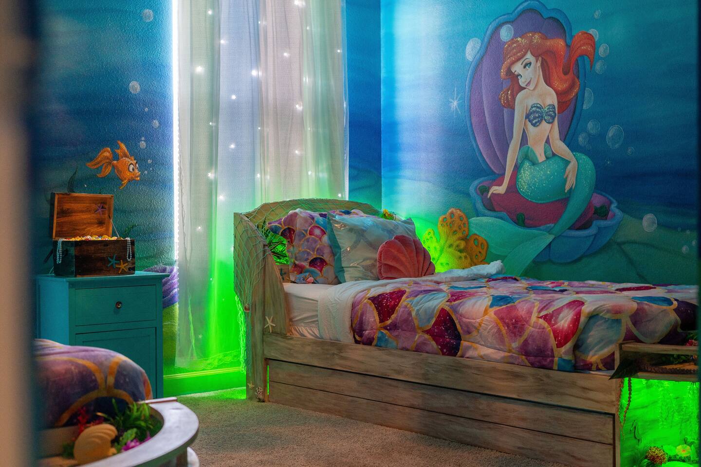 Twin boat beds beneath a hand-painted mermaid mural with twinkle-light curtains