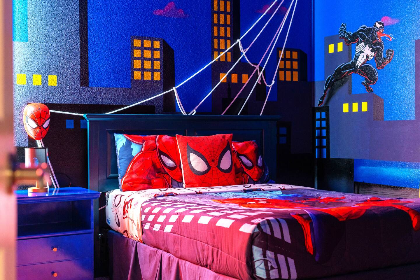 Spider-Man bedding and mask lamp beneath a Venom mural detail