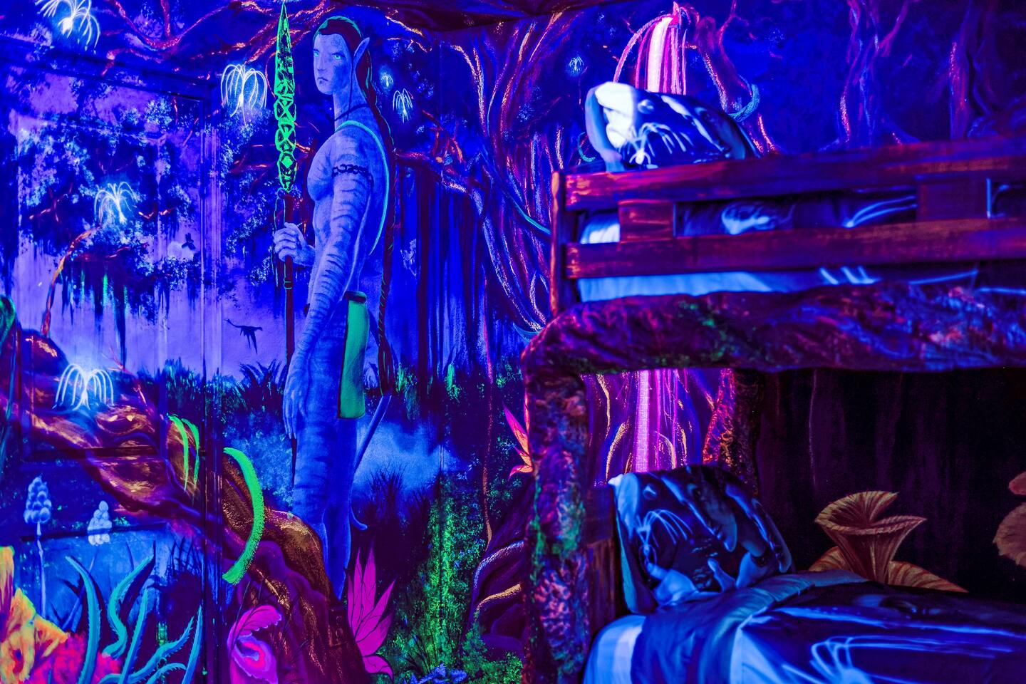 Hand-painted Pandora mural wraps the bunk beds in the black-light Avatar room