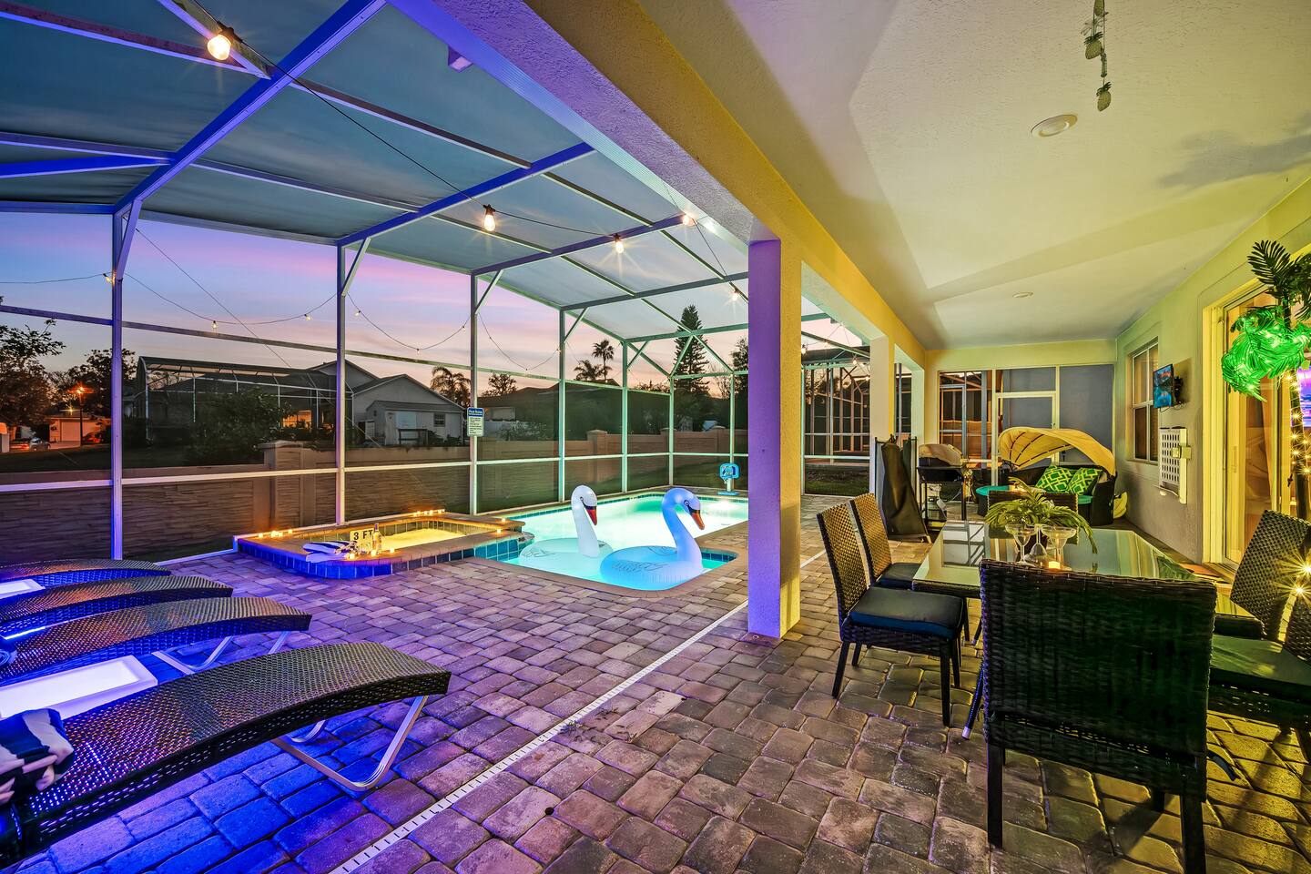 Covered lanai with outdoor dining, TV, daybed, and grill beside the pool