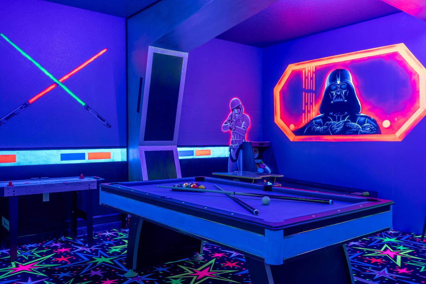 Pool table beneath the glowing Darth Vader mural in the black-light arcade