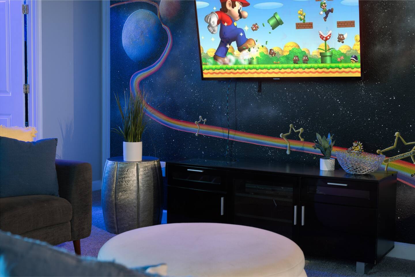 Galaxy movie loft with rainbow-road space mural and wall-mounted TV