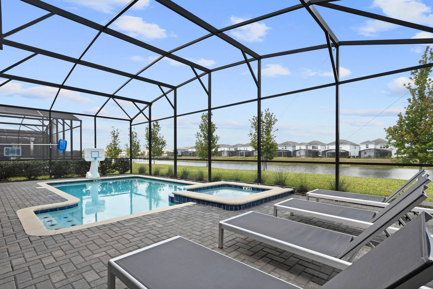 Pool deck with loungers, hot tub, and lake view