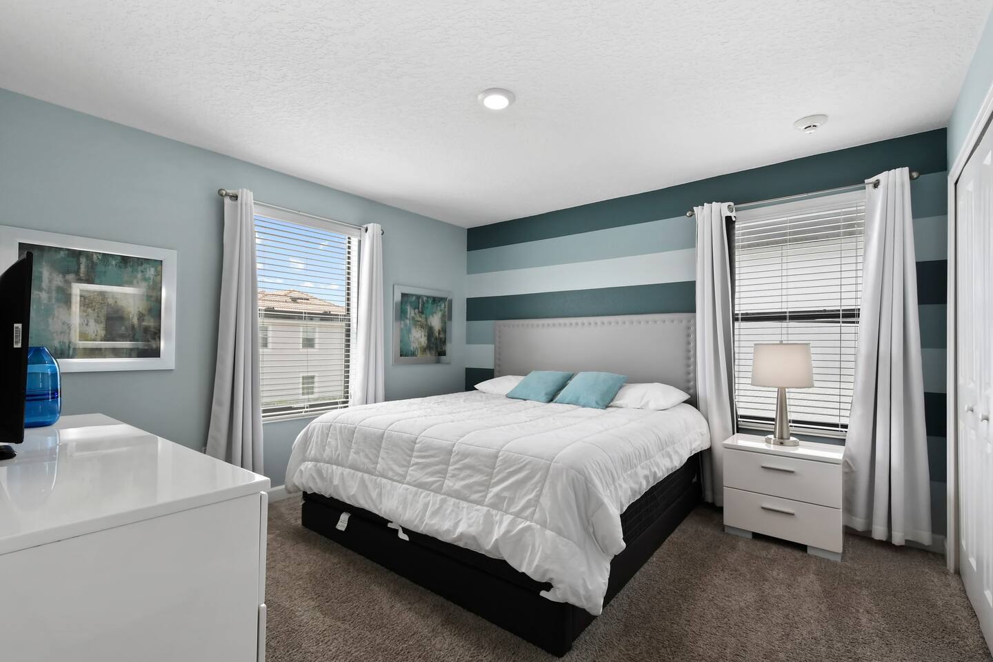 King bedroom with teal striped accent wall and bedside lamp