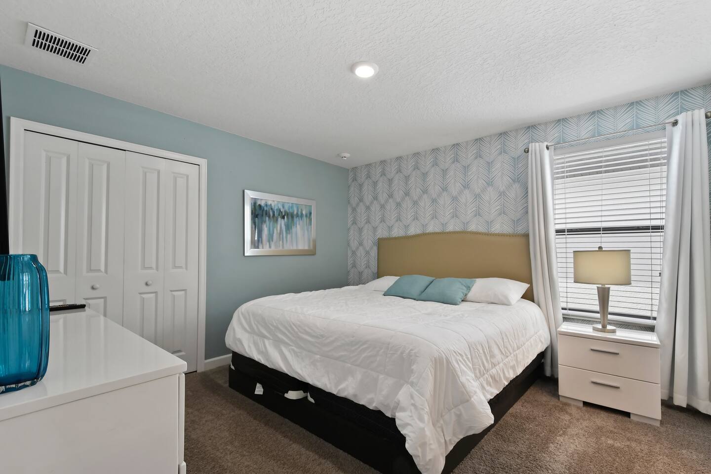 King bedroom with leaf-print wallpaper accent wall