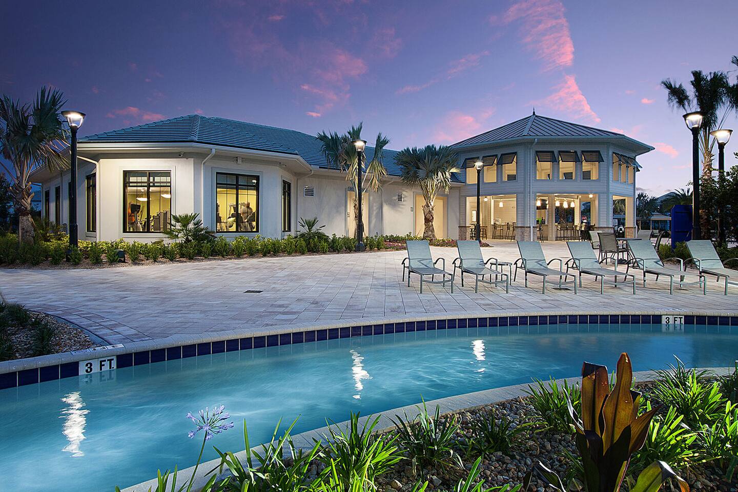 Resort clubhouse and pool deck with loungers at dusk