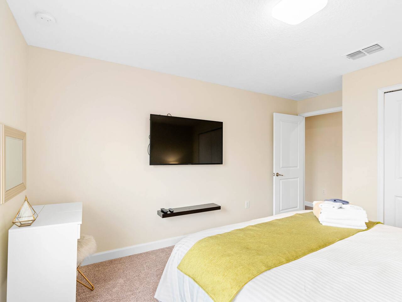 Bright room with plush bedding, modern decor, and a wall-mounted TV for entertai