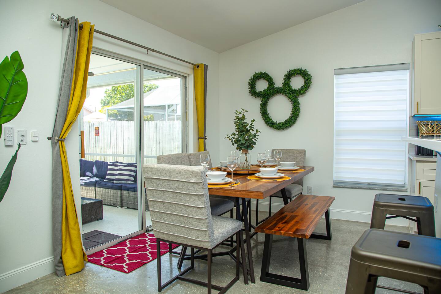 Dining table set for four beside a Mickey topiary and a sliding door to the pati