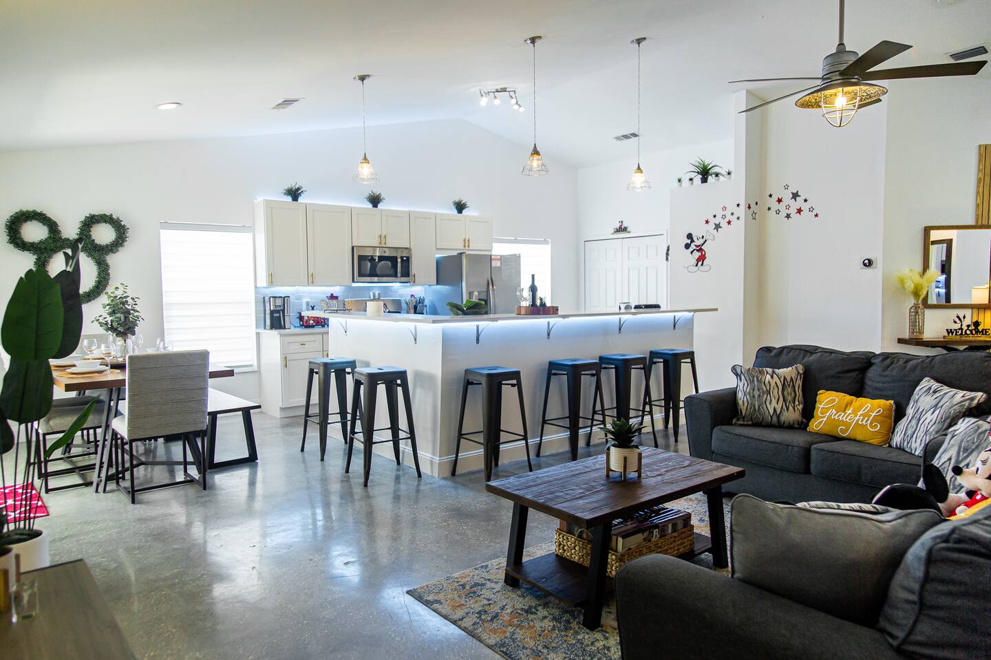 Open-concept kitchen island with bar stools, a dining table, and the living room