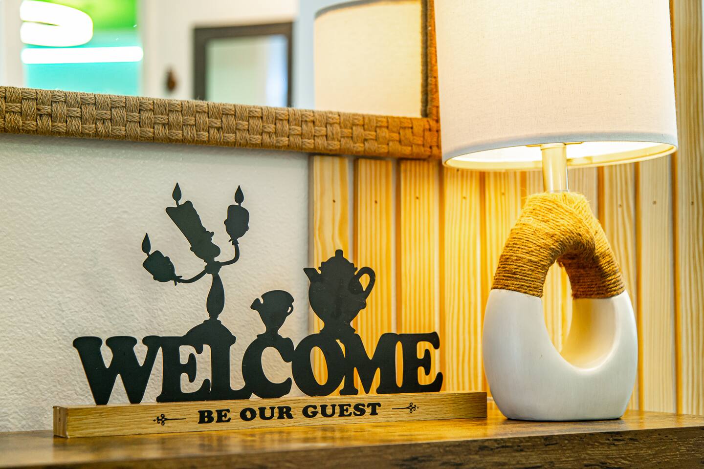 Welcome Be Our Guest sign and a lamp on a console table.