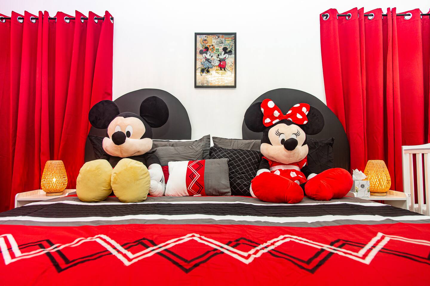 Mickey master bedroom with a king bed, plush toys, and red curtains.