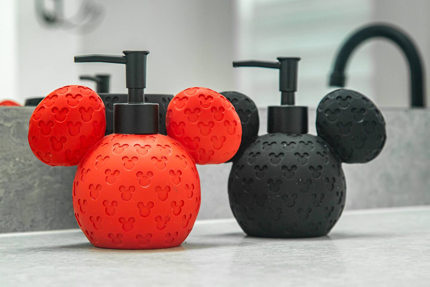 Red and black Mickey-shaped soap dispensers on a bathroom vanity.