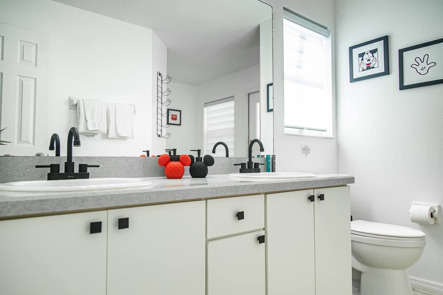 Bathroom with a double vanity, walk-in shower, and Mickey wall art.
