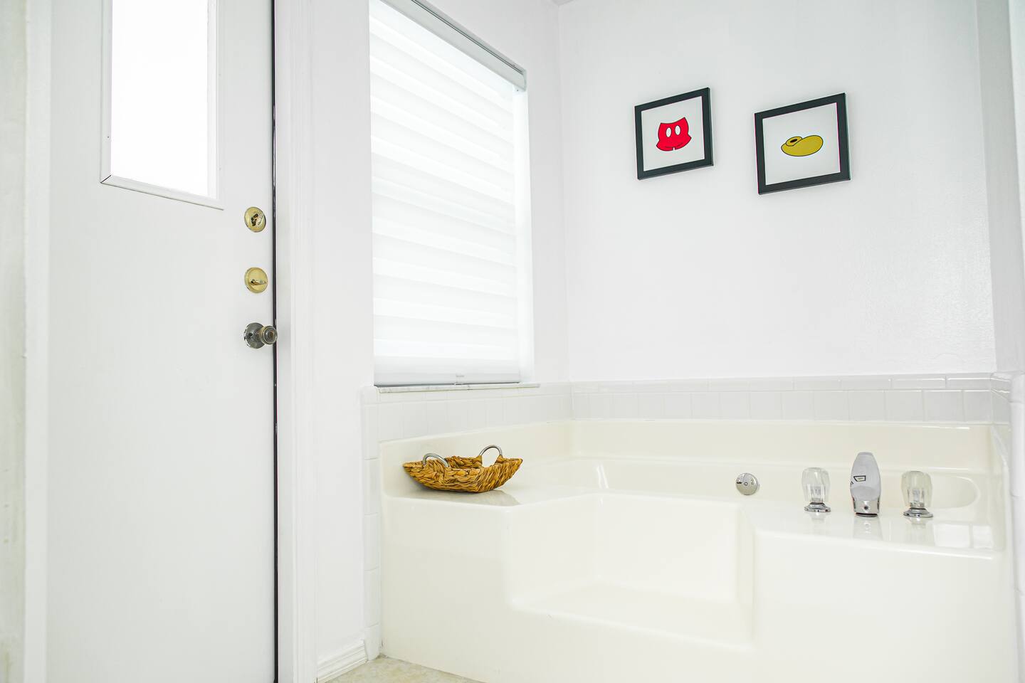 Bathroom soaking tub below framed Mickey-themed art.