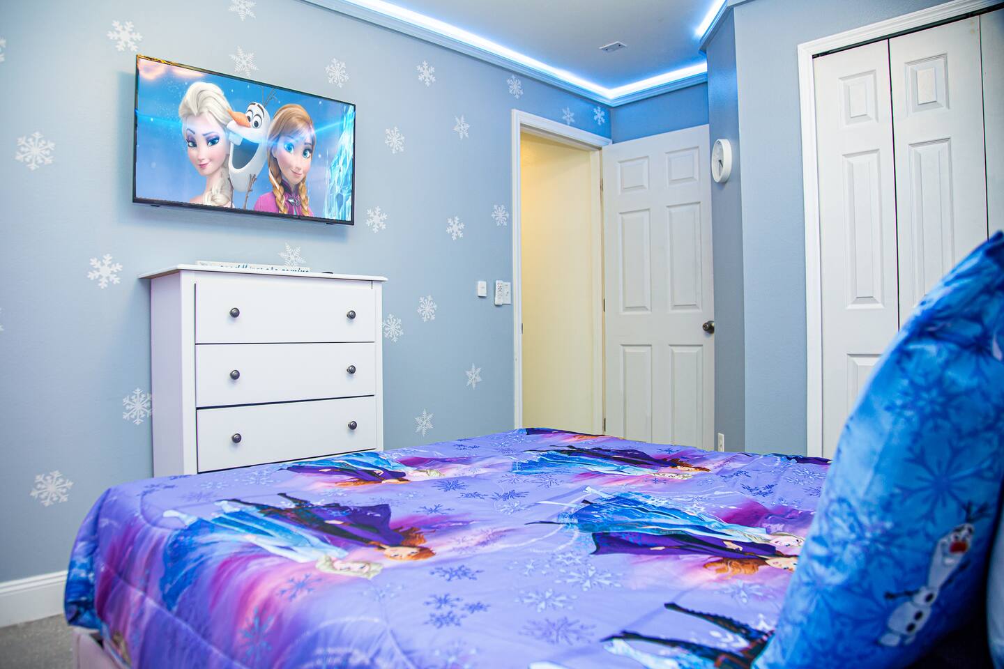 Frozen bedroom with a wall-mounted TV and a white dresser.