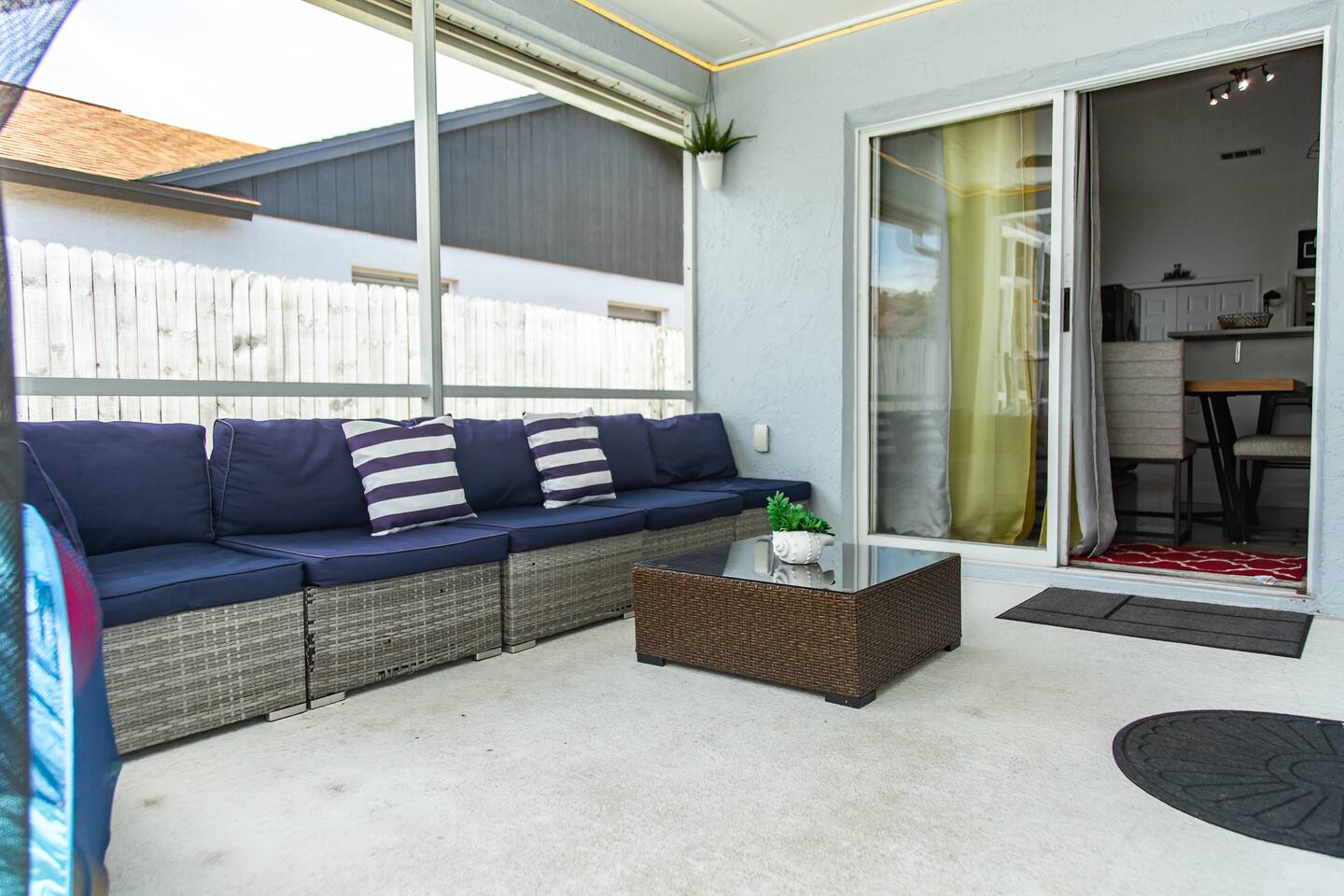Covered screened lanai with a navy sectional and a sliding door to the interior.