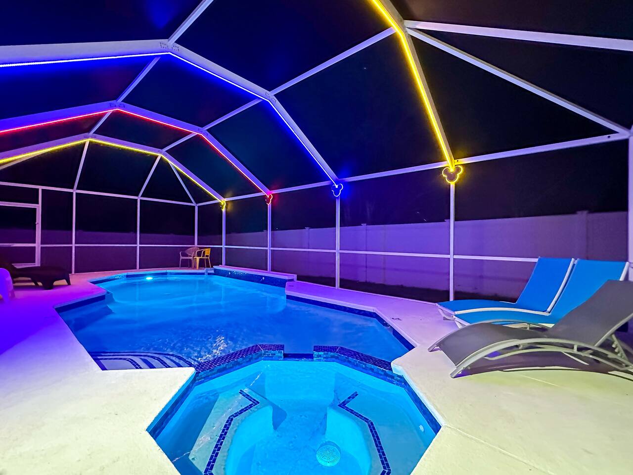 Night view of the pool and spa with colorful LED cage lighting.