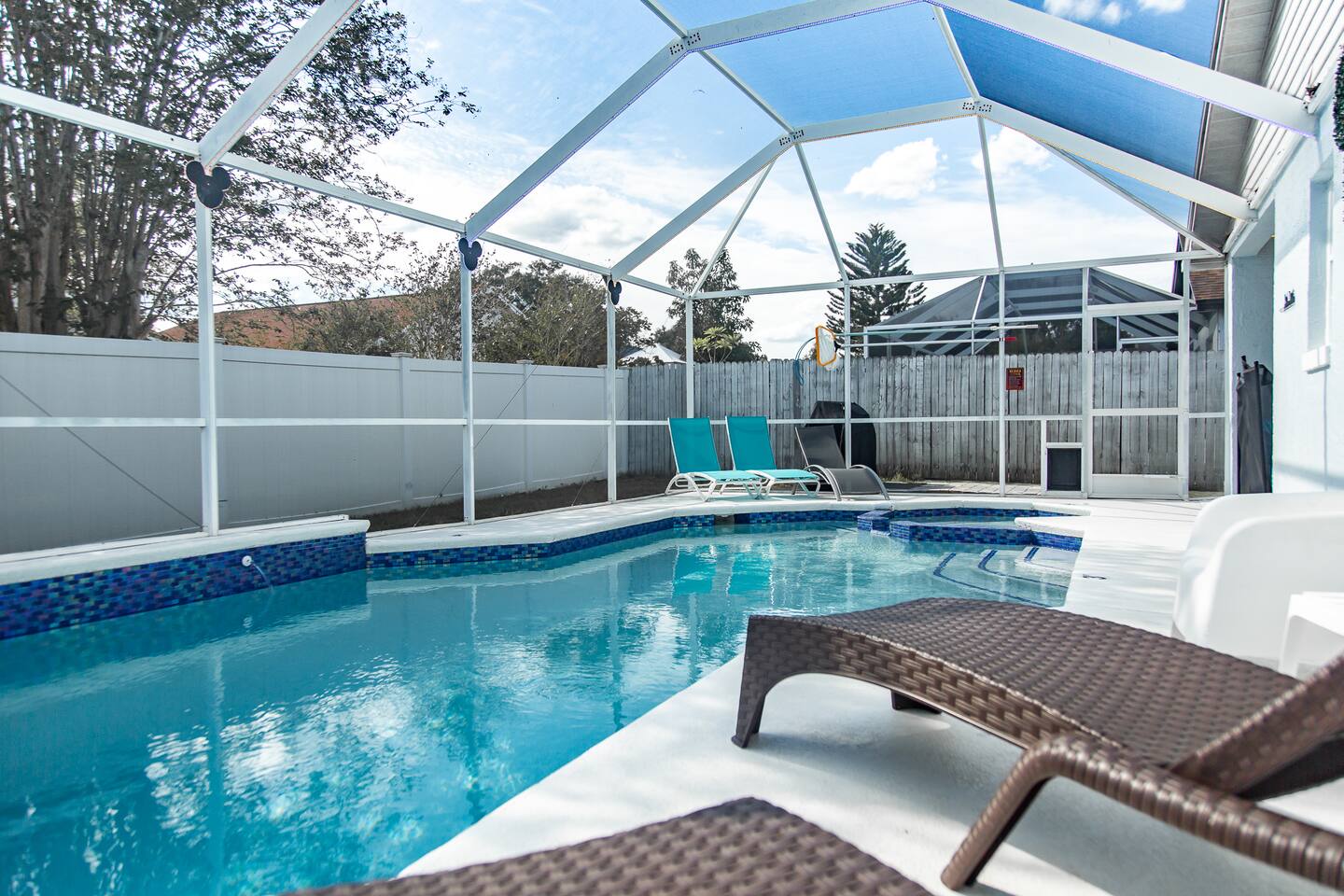 Daytime screened pool with lounge chairs and a BBQ grill.
