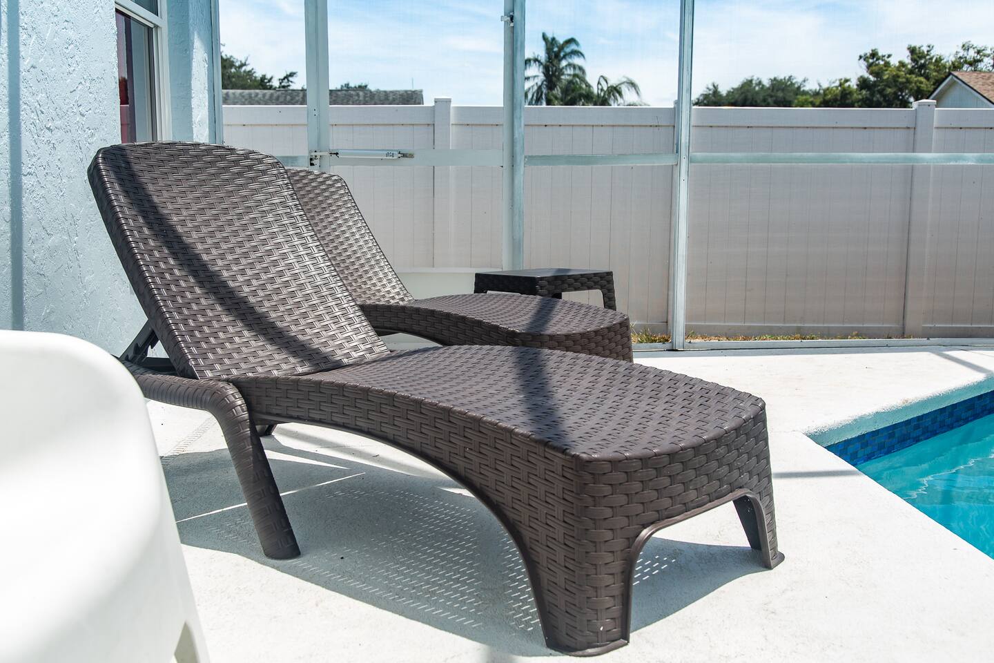 Brown wicker chaise lounge beside the pool.