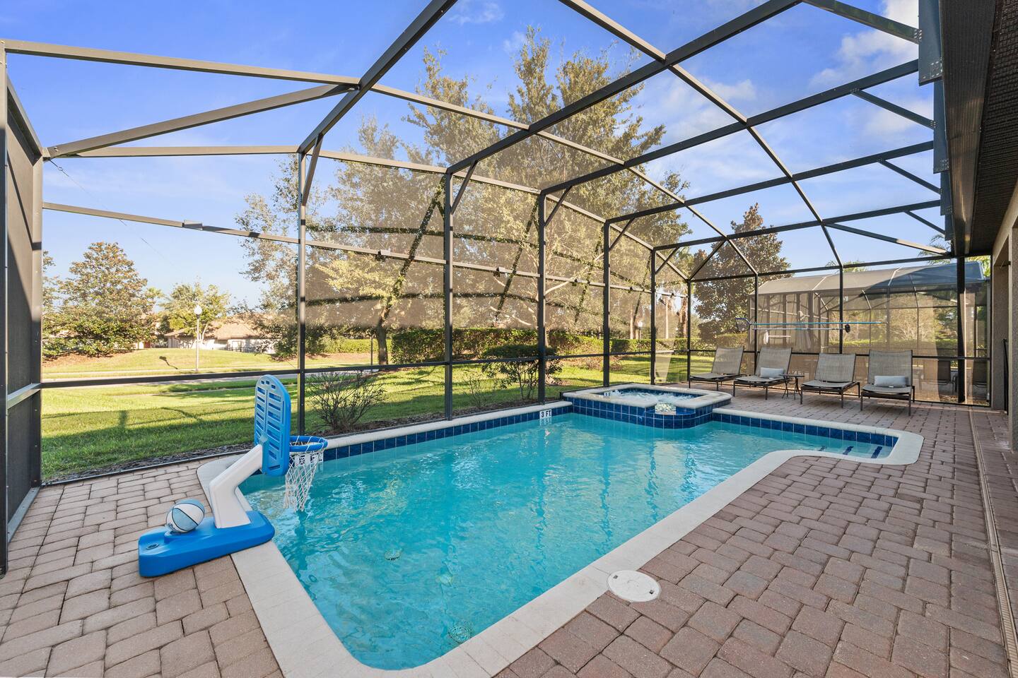Screened private pool with its own basketball hoop and attached spa, looking out