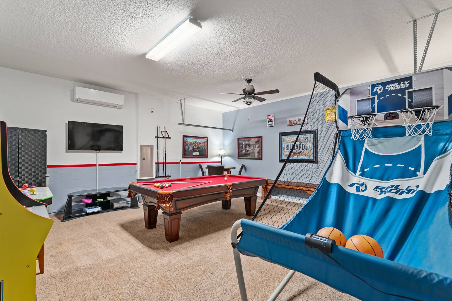 Another angle of the game room with wall-mounted TV, foosball and arcade corner.