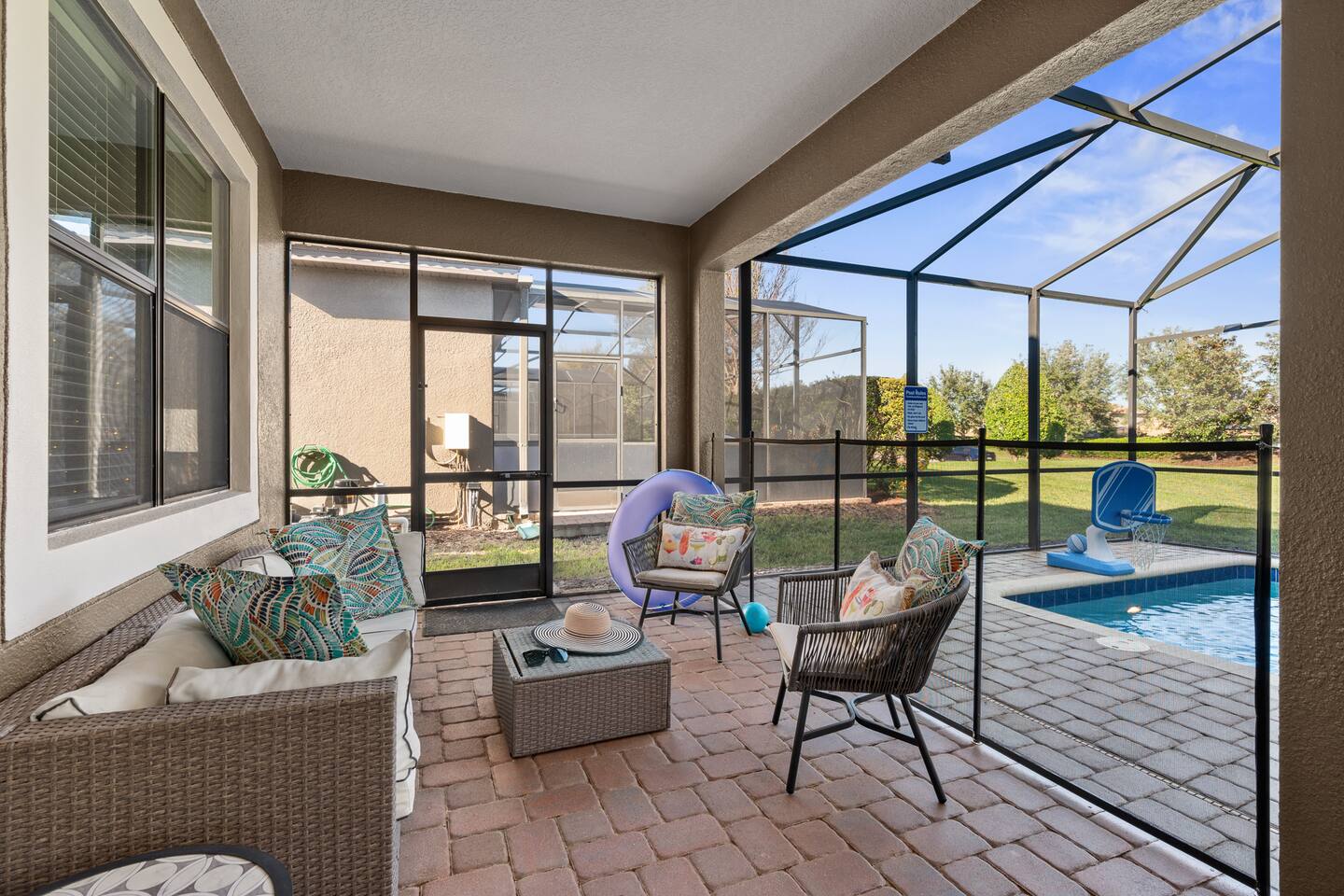 Covered lanai lounge seating beside the pool, protected by a child-safety fence.