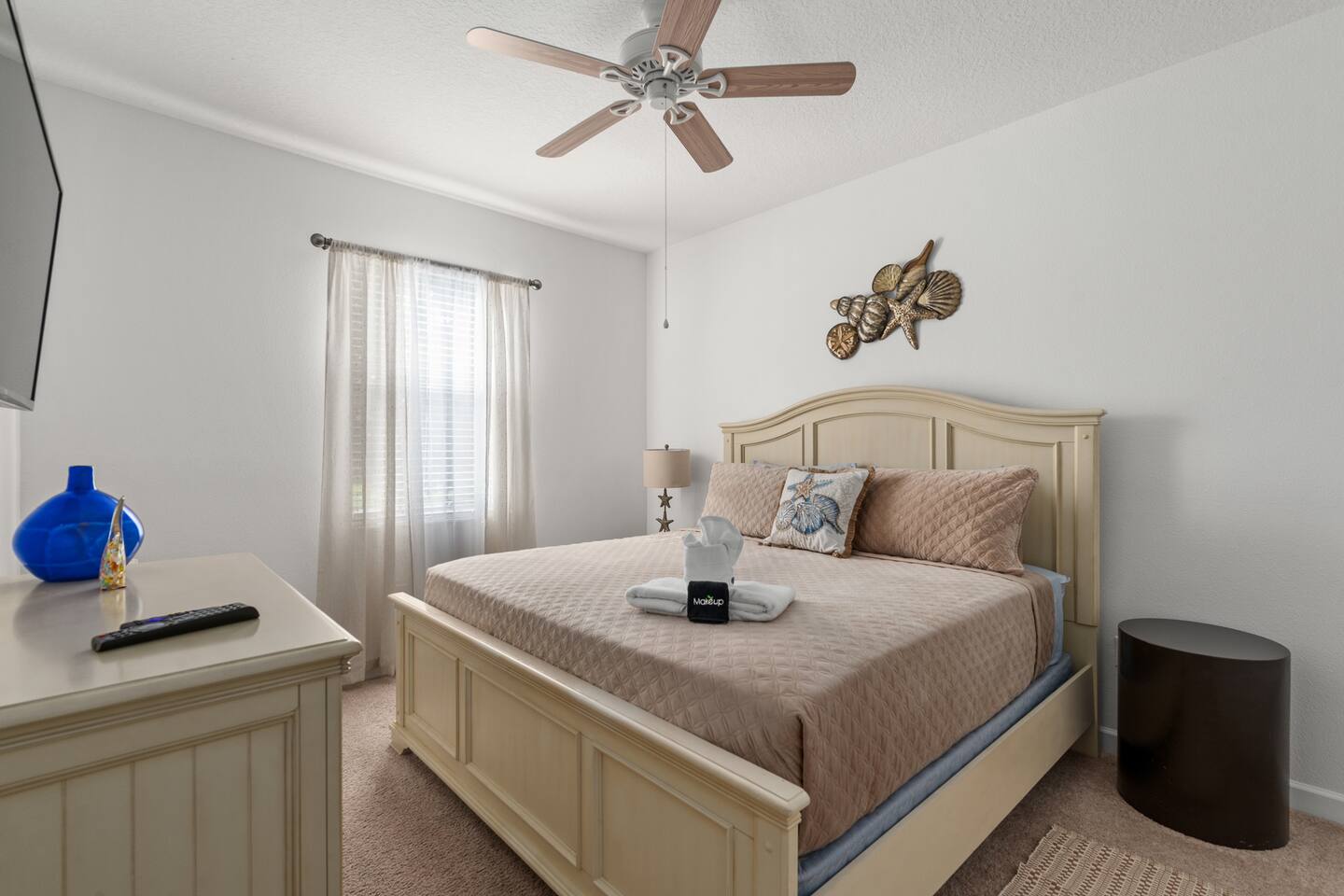 Coastal king suite in soft creams with seashell accents above the bed.