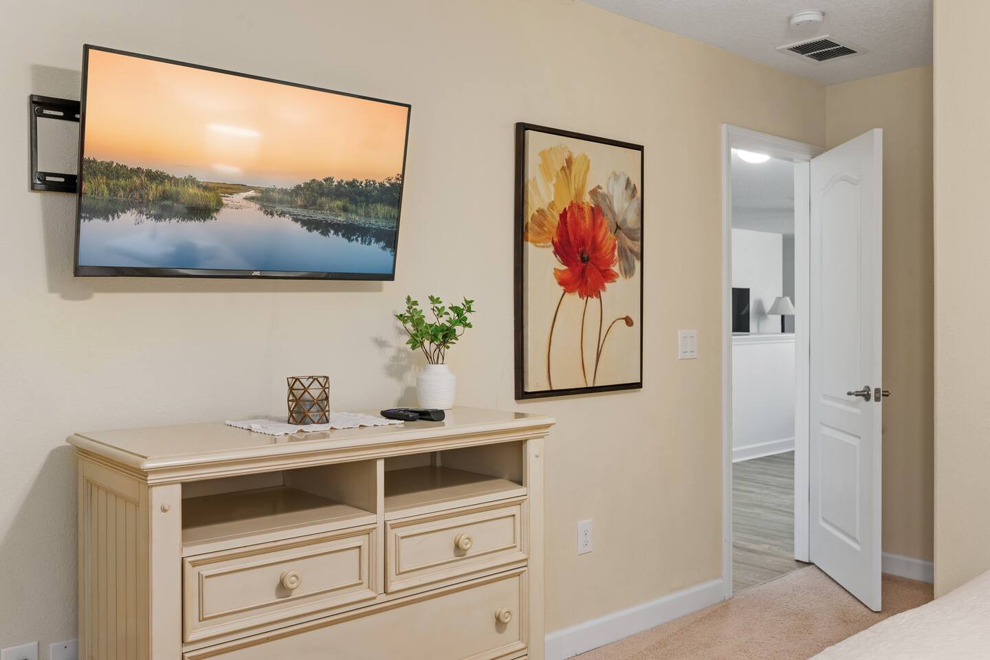 The flower room's dresser and TV beneath a bright poppy canvas.