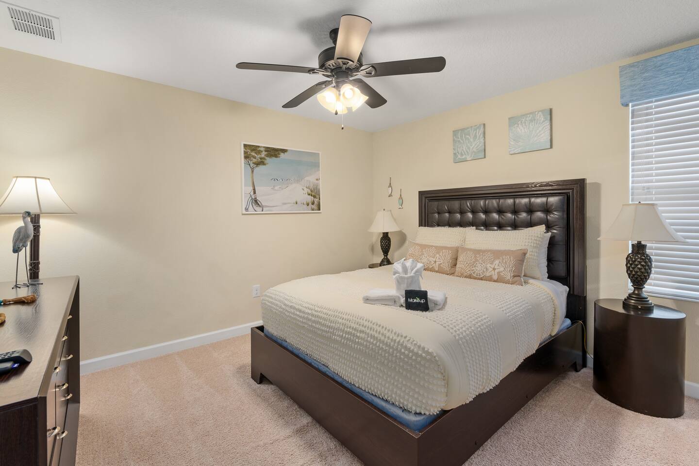 Beach-themed queen room with tufted headboard and coastal artwork.