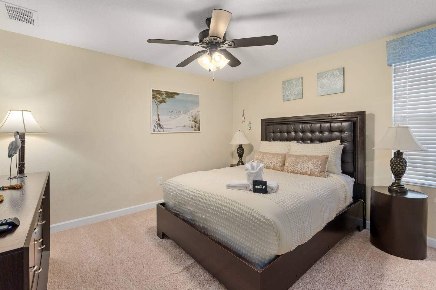 The coastal queen room with tufted headboard, coral prints and beachy lamps.