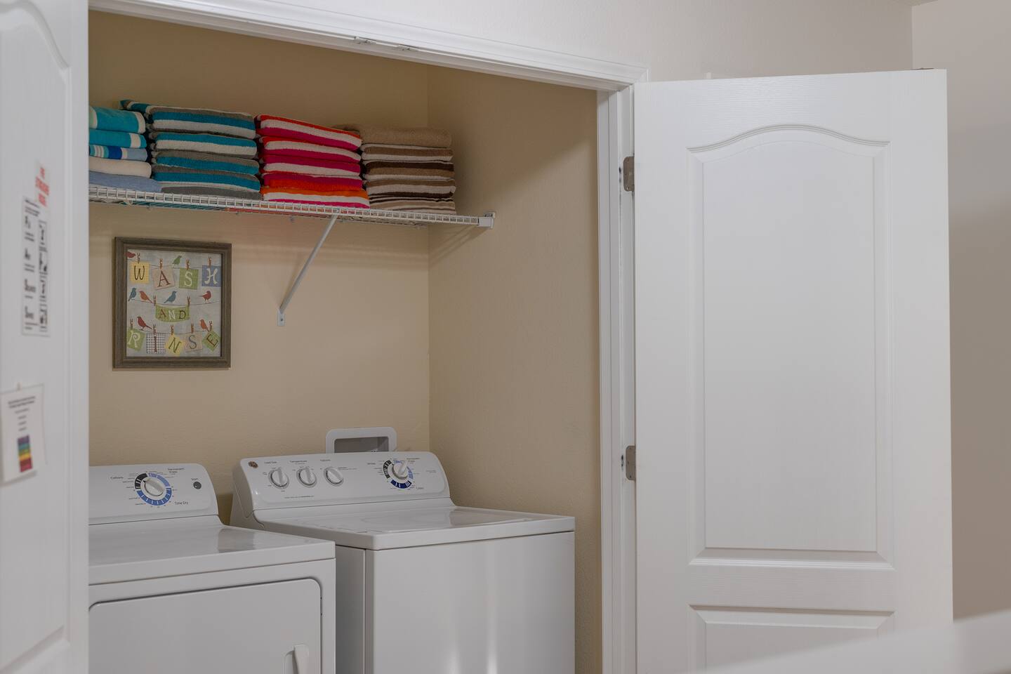 Laundry closet with full-size washer and dryer, stocked with fresh towels.