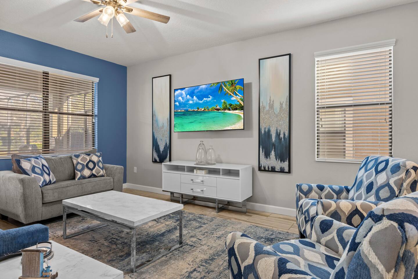Living room with wall-mounted TV, white media console, patterned armchairs, and 