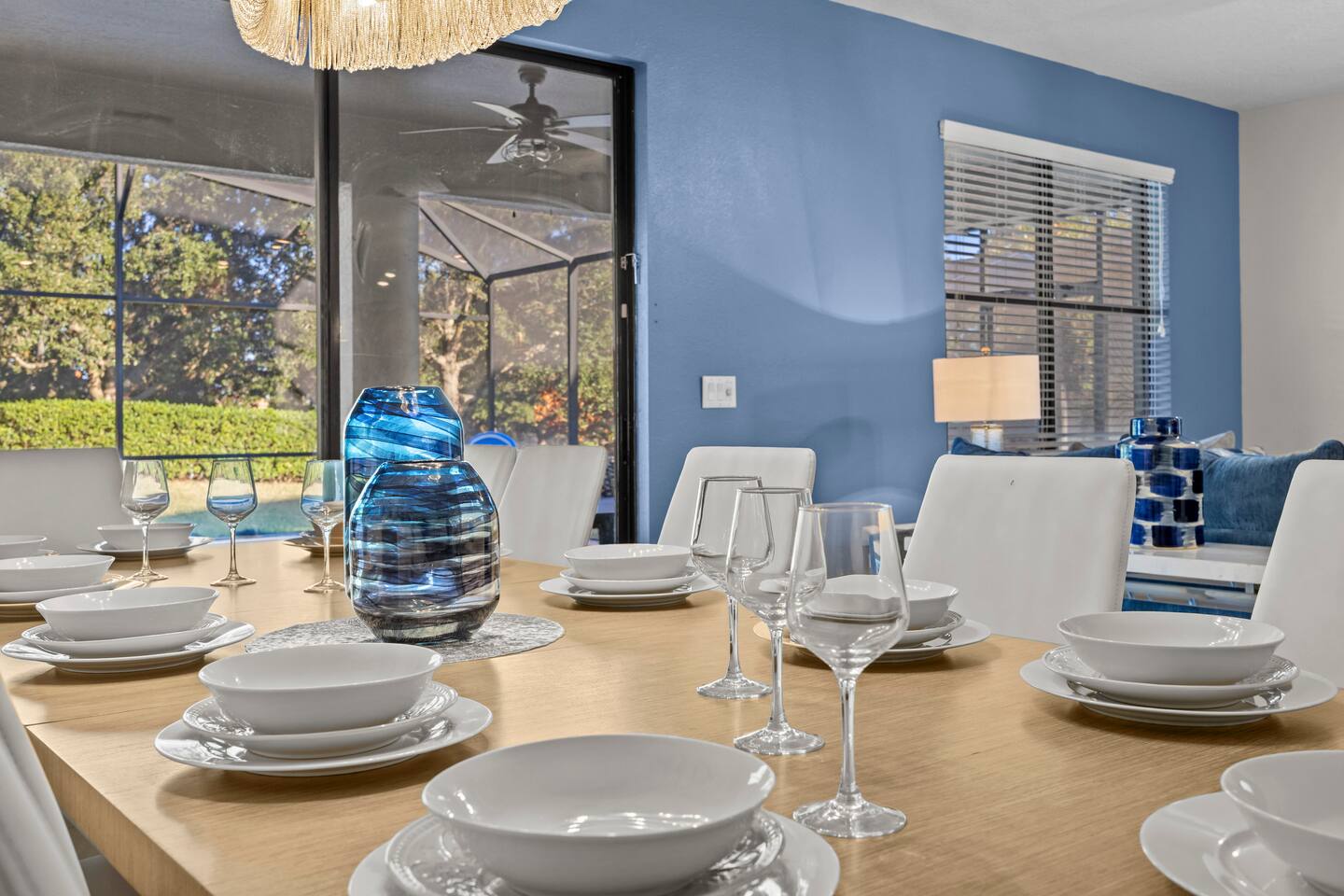 Dining table close-up with place settings, stemware, and blue art-glass centerpi