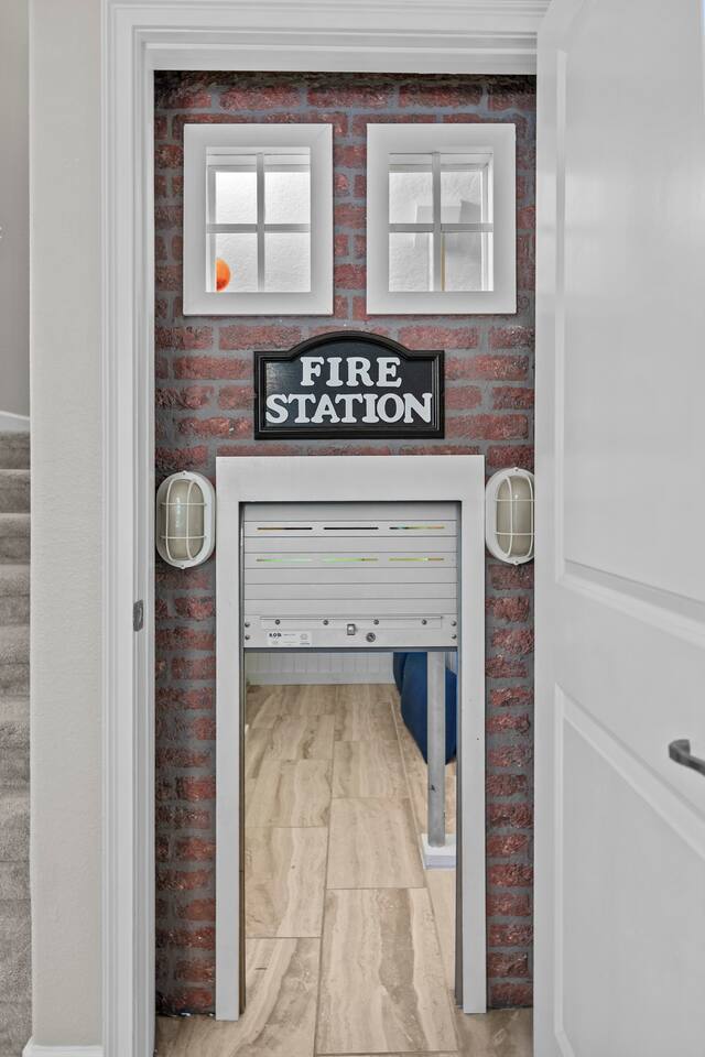 Close-up of the fire-station playhouse entrance with brick facade, sign, and rol