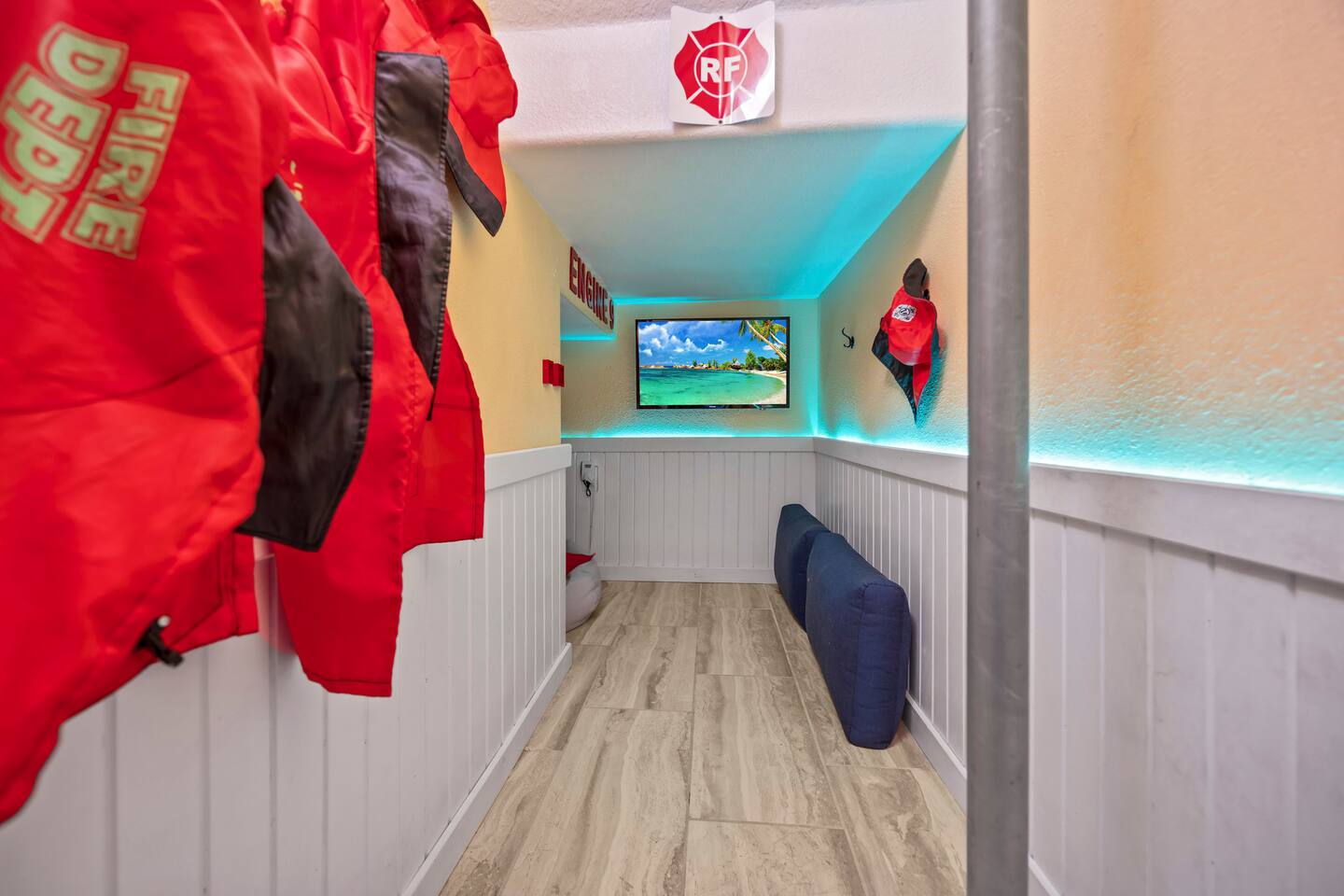 Fire-station play nook with hanging firefighter jackets, fire pole, cushions, an