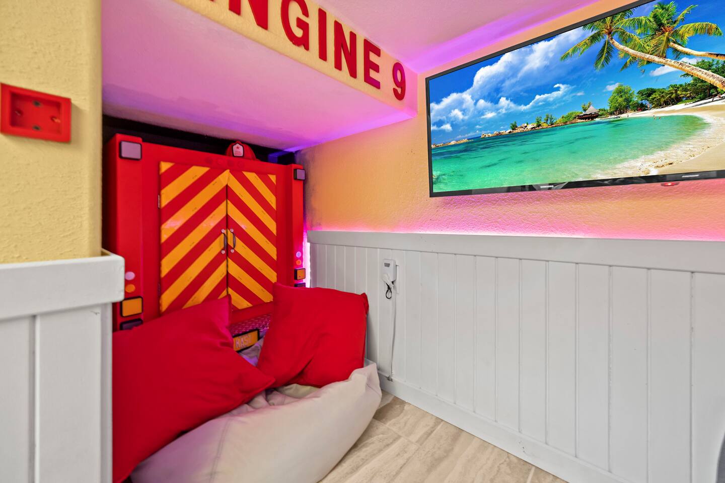 Engine 9 play area with striped fire-truck cabinet, red cushions, and wall-mount