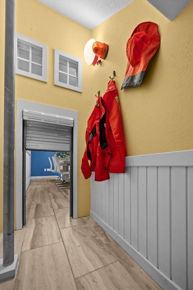 Fire-station playroom corridor with costume hooks, play helmet, and roll-up door