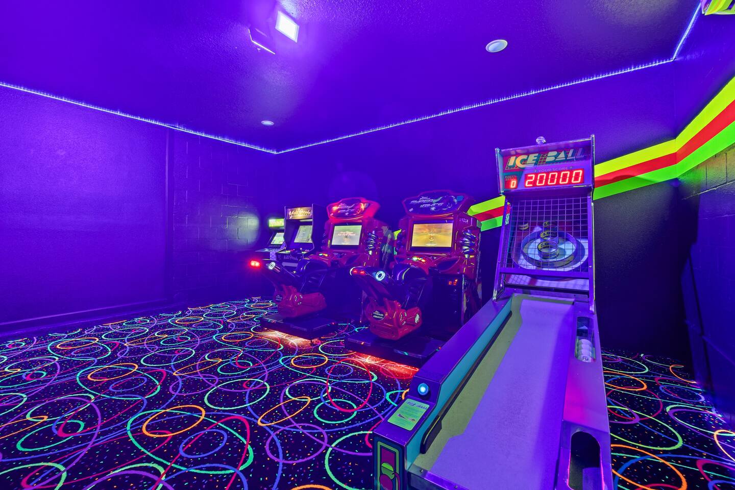 Skee-ball machine and racing simulators in the neon-lit arcade room